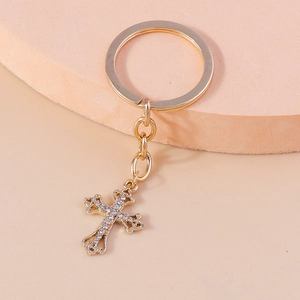 Close-up of golden Christian cross keychain with sparkling white rhinestones on steps