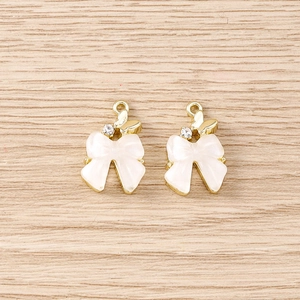 Détail de pendentifs bijoux en forme de nœud avec placage d'or et strass sur bois