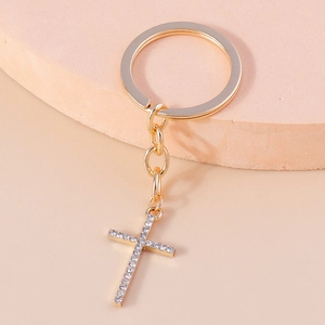 Detail of a gold-plated Christian cross keychain with sparkling rhinestone inlay