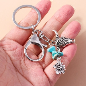 Detail of vintage bohemian bull head keychain with turquoise stones and silver flower charm