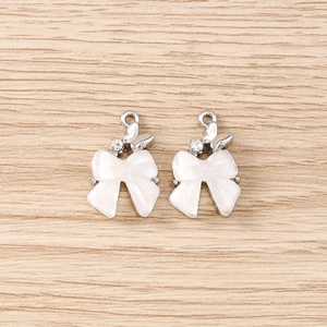 Détail de pendentifs nœuds en émail blanc avec papillon argenté et strass pour bijoux DIY