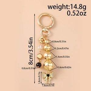 Detailed gold keychain with beads, black heart bow charm, and spring ring clasp