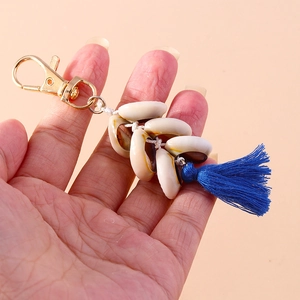 Detail of seashell tassel keychain with gold lobster clasp and blue bohemian fringe