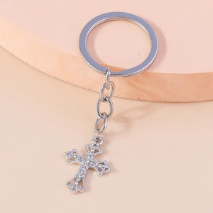 Detailed close-up of a silver cross keychain with sparkling rhinestones on a pedestal