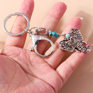 Detail of vintage silver elephant keychain with hollow patterns and turquoise beads