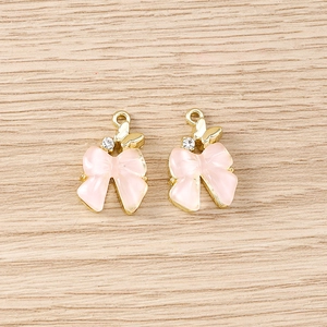 Détail de pendentifs nœuds roses avec papillon doré et accents en strass
