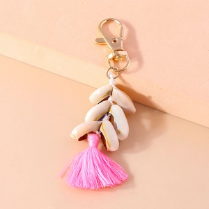 Macro view of shell tassel keychain with natural conch shells and pink thread on peach background