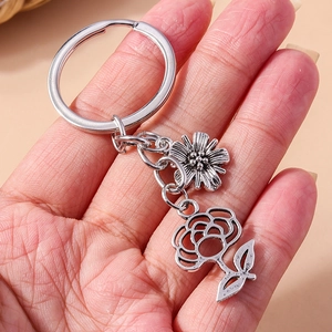 Detail view of silver floral keychain featuring daisy and rose charms in a palm display