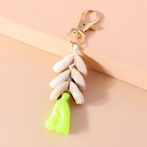 Detail of seashell keychain with golden lobster clasp and vibrant neon green tassel