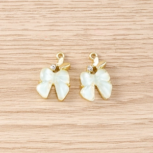 Gros plan de pendentifs en forme de nœud avec éclat d'opale et petits papillons dorés pour bijoux