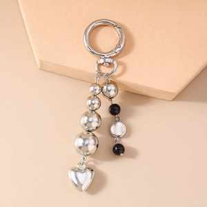 Macro detail of silver keychain featuring metallic beads and a polished heart pendant charm