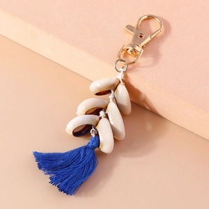 Detailed close-up of a conch seashell keychain with blue tassel and golden clasp
