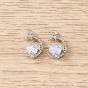 Détail de pendentifs lune et étoile en argent avec pierres irisées et perles