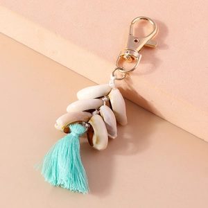 Detail view of gold lobster clasp with natural white shells and mint green tassel charm