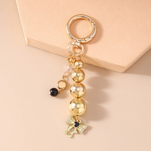 Detailed close-up of gold keychain featuring a black heart crystal and beaded bow charm