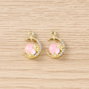 Gros plan de pendentifs lune dorés avec pierre œil de chat rose et petits cristaux