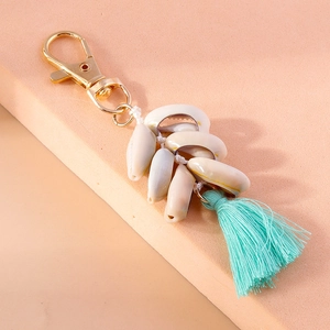 Detailed close-up of bohemian shell keychain with mint green tassel and gold lobster clasp