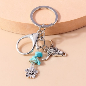 Close-up of vintage western style silver bull head keychain with turquoise beads and daisy
