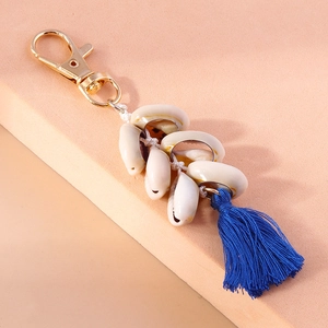 Detail of bohemian shell keychain featuring white shells and a long navy blue silk tassel