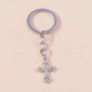 Close-up of silver-tone rhinestone cross keychain with baroque style and crystal details