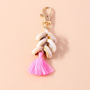 Detailed view of the beach cowrie shell keychain with vibrant pink silk tassel and gold clasp