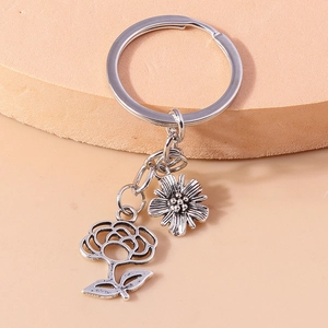 Detailed close-up of retro silver metal keychain with rose and daisy floral charms