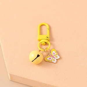 Close-up of a yellow butterfly enamel charm with small bell on a lobster clasp keychain