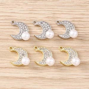 Détail de pendentifs croissant de lune avec pavé de cristaux et perle en or et argent