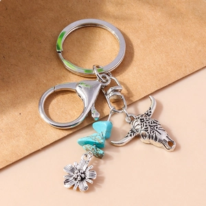 Macro detail of ethnic keychain featuring a bull skull, turquoise stones, and silver flower