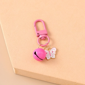 Detailed macro shot of pink butterfly keychain with bell on matte surface