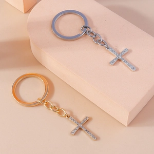 Close-up of gold and silver rhinestone cross keychains on beige geometric display blocks