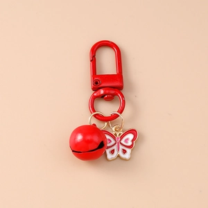 Macro detail of red spring D-buckle with metal bell and enamel butterfly pendant