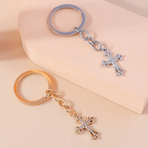 Detail of gold and silver hollow cross keychains with rhinestones on a beige pedestal