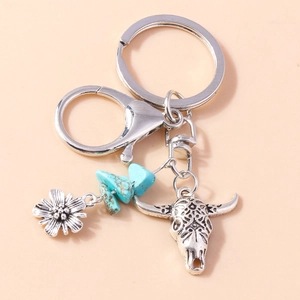 Detailed close-up of retro bull skull keychain with turquoise beads and floral pendant