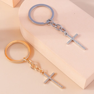 Detail of silver and gold cross keychains with rhinestones on geometric stands