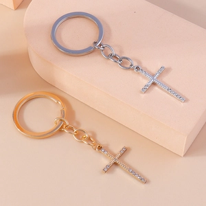 Detail of silver and gold cross keychains with rhinestones on a soft pink background