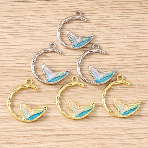 Détail de pendentifs queue de sirène baroques avec émail coloré sur surface en bois