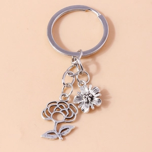 Close-up of vintage silver keychain with hollow rose and daisy charms on orange background