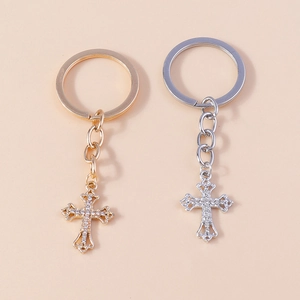Detailed view of gold and silver hollowed-out cross keychains with crystal rhinestones