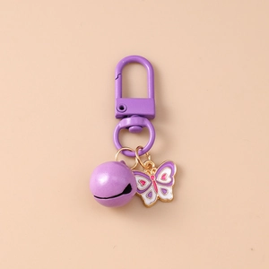Detail of purple butterfly keychain with bell and D-ring buckle on beige background