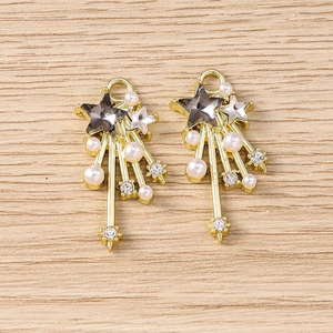 Detailed close-up of Y2K star charms with rhinestones and pearls on a light wood surface
