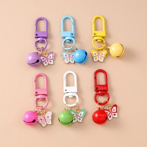 Flat lay of six colorful butterfly bell keychains with oil drip finish on beige background
