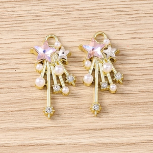 Detail of star-shaped pendants with pink heart crystal and pearls on wood background