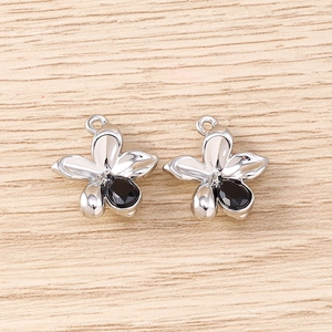 Détail de deux pendentifs fleurs argentés avec cristaux noirs pour création de bijoux