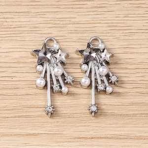 Detail of Y2K star pendants with rhinestones, pearls and metallic tassels on wood surface
