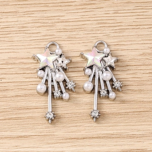 Detail of silver Y2K star pendants with faux pearls and rhinestones on wood texture