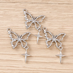 Detail of butterfly pendants with white pearls and rhinestones on wood background