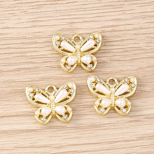 Macro view of gold butterfly pendants with white pearls and rhinestones for DIY jewelry