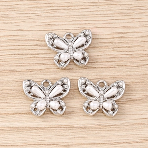 Detailed view of alloy butterfly charms with inlaid pearls and rhinestones on wood