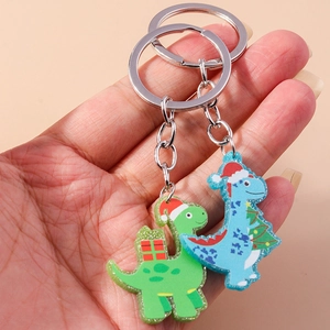 Handheld view of Christmas themed dinosaur keychains with green and blue acrylic figures
